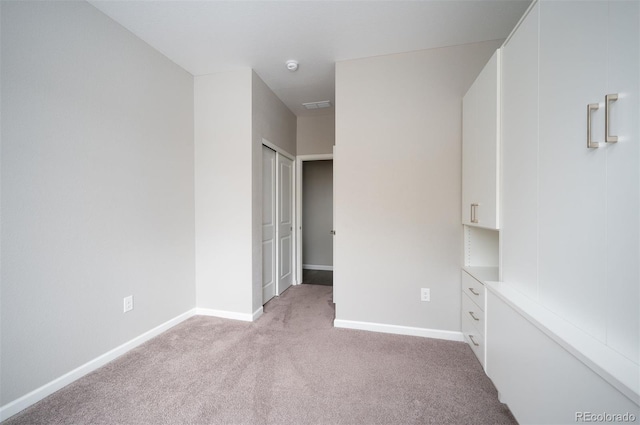 unfurnished bedroom featuring light carpet, visible vents, and baseboards