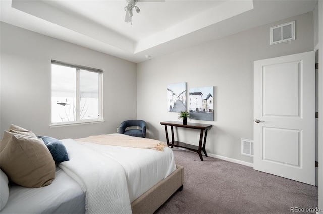 bedroom featuring carpet flooring, a raised ceiling, visible vents, and baseboards