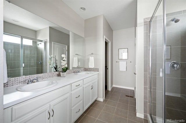 bathroom featuring double vanity, a stall shower, tile patterned flooring, and a sink