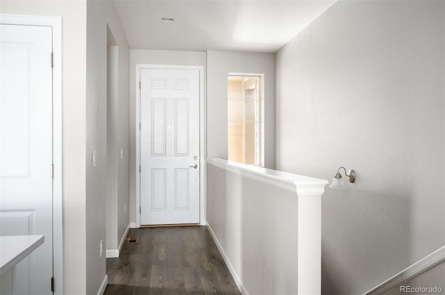 hallway featuring baseboards and dark wood-type flooring