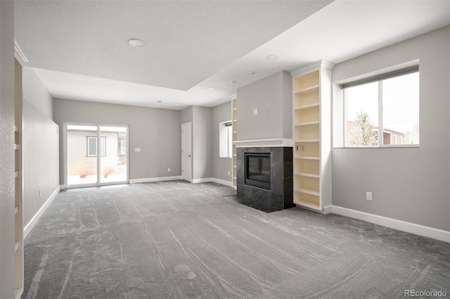 unfurnished living room with baseboards, a wealth of natural light, and a tile fireplace