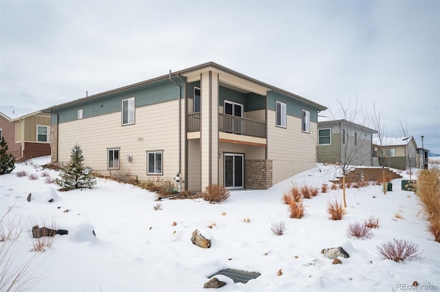 snow covered property with a garage and a balcony