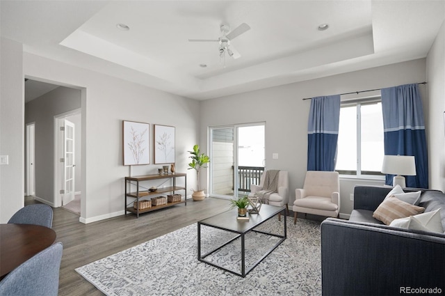 living area featuring a raised ceiling, wood finished floors, plenty of natural light, and recessed lighting