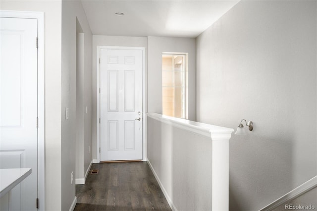 corridor with dark wood-type flooring and baseboards