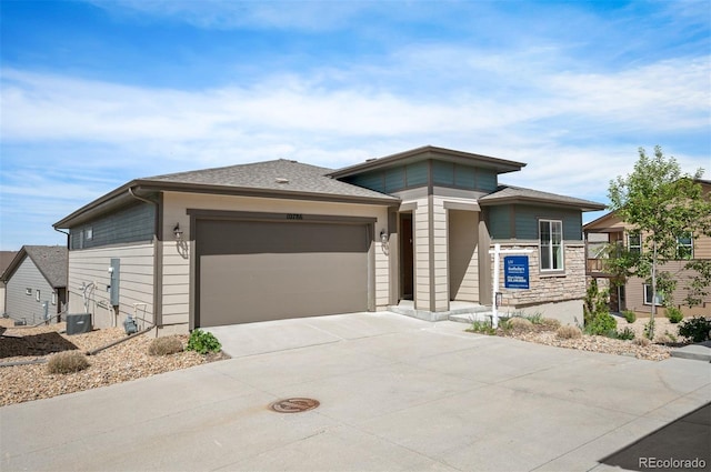 10786 Bear Cub Dr, Broomfield, CO 80021 - prairie-style home featuring a garage, concrete driveway, stone siding, and central AC