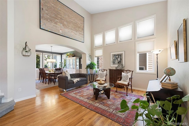 85 Willowleaf Dr, Littleton, CO 80127 - living area featuring arched walkways, wood finished floors, a towering ceiling, and baseboards