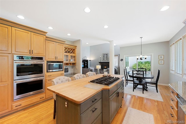 85 Willowleaf Dr, Littleton, CO 80127 - kitchen featuring appliances with stainless steel finishes, a kitchen breakfast bar, light wood-style floors, a chandelier, and decorative columns