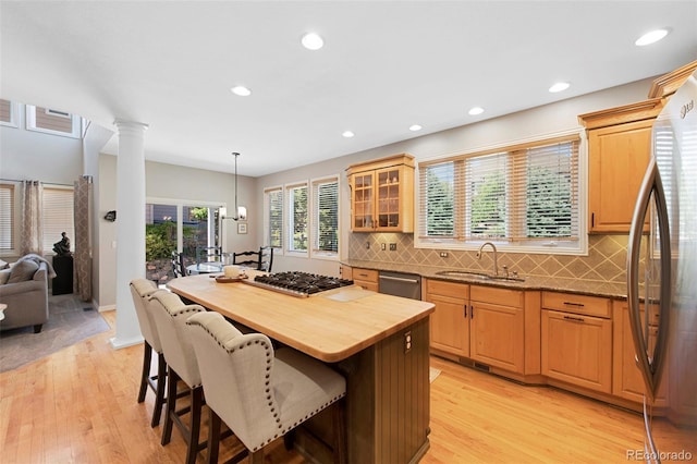 85 Willowleaf Dr, Littleton, CO 80127 - kitchen with a sink, appliances with stainless steel finishes, a kitchen breakfast bar, decorative columns, and light wood-style flooring