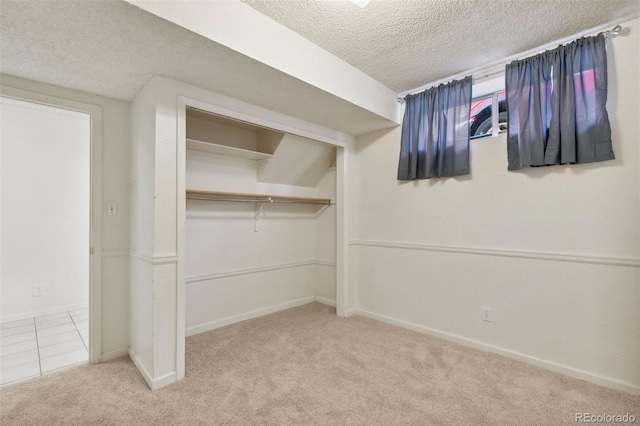 interior space with light colored carpet, a textured ceiling, and a closet