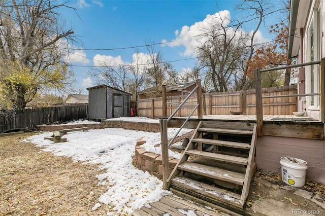 snowy yard featuring a shed and a deck