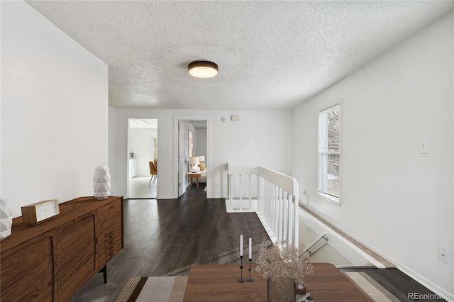 corridor with a textured ceiling and dark hardwood / wood-style floors