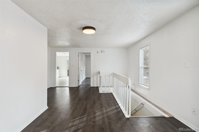 hall with dark hardwood / wood-style flooring and a textured ceiling