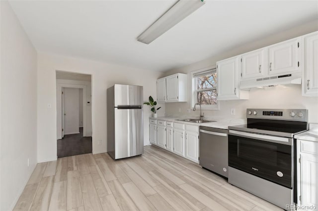 kitchen featuring appliances with stainless steel finishes, light hardwood / wood-style flooring, white cabinetry, and sink