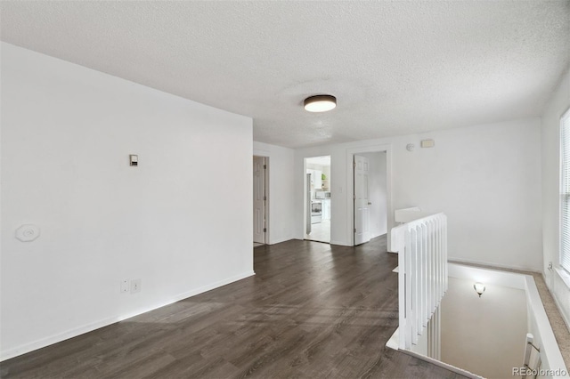 spare room featuring a textured ceiling and dark hardwood / wood-style flooring