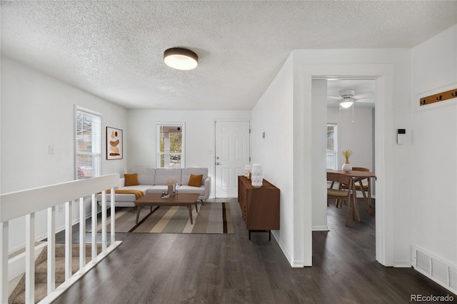 interior space with a textured ceiling, ceiling fan, and dark wood-type flooring