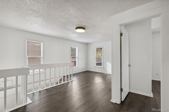 empty room featuring a textured ceiling and dark wood-type flooring