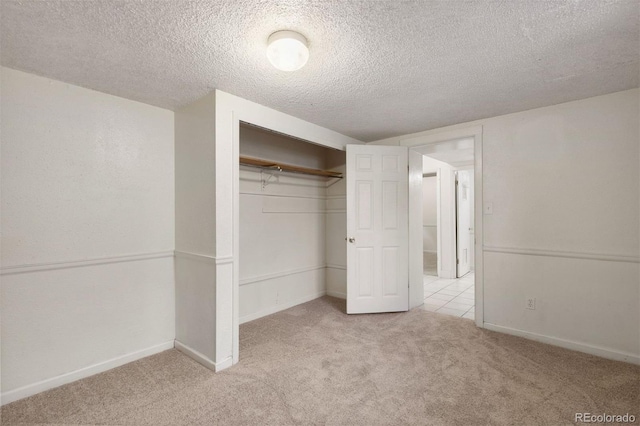 unfurnished bedroom featuring a textured ceiling, light colored carpet, and a closet