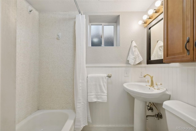 bathroom featuring toilet, shower / bath combo with shower curtain, and a textured ceiling