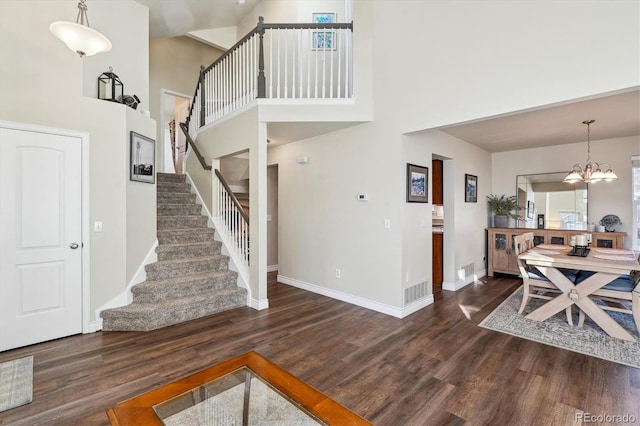 interior space featuring an inviting chandelier, a towering ceiling, and dark hardwood / wood-style floors