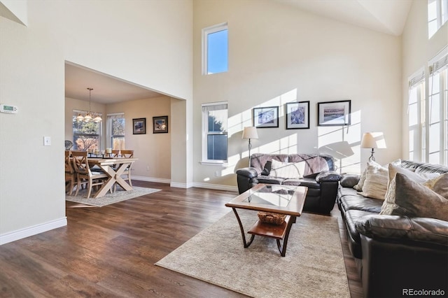 living room with a towering ceiling, dark hardwood / wood-style flooring, and a chandelier