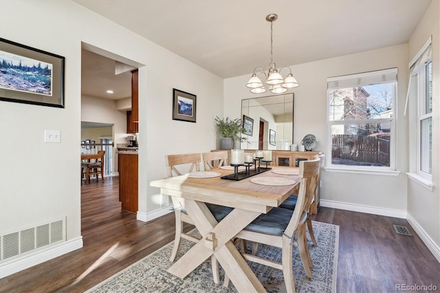 dining space with dark wood-type flooring and an inviting chandelier