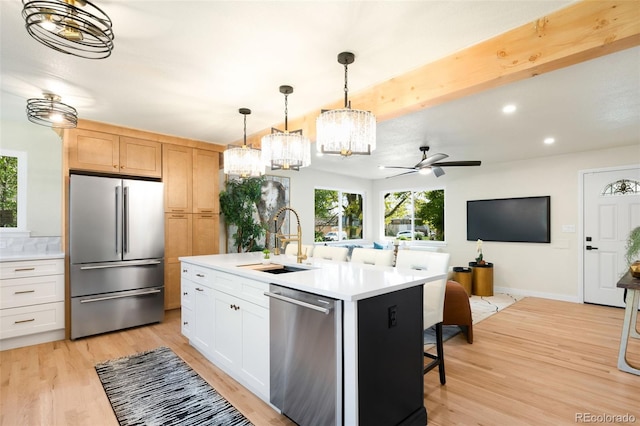 6512 Upham St, Arvada, CO 80003 - kitchen featuring stainless steel appliances, a sink, a chandelier, light wood-style floors, and open floor plan