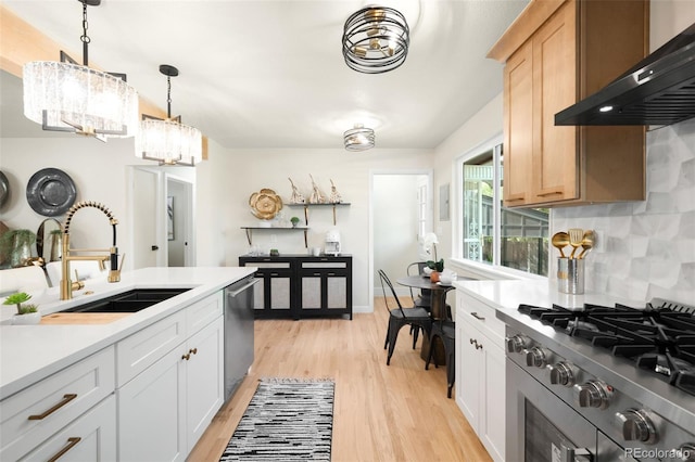 6512 Upham St, Arvada, CO 80003 - kitchen with wall chimney exhaust hood, stainless steel appliances, a sink, light wood-style flooring, and light countertops