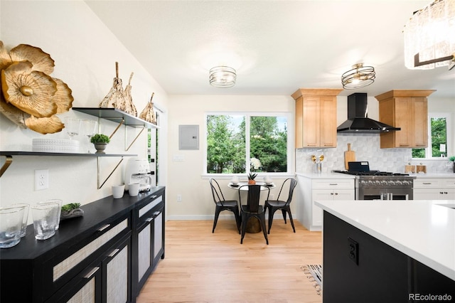6512 Upham St, Arvada, CO 80003 - kitchen with wall chimney exhaust hood, high end stove, light brown cabinetry, light wood-type flooring, and light countertops