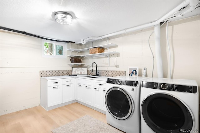 6512 Upham St, Arvada, CO 80003 - laundry area with separate washer and dryer, cabinet space, light wood finished floors, and a textured ceiling