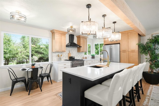 6512 Upham St, Arvada, CO 80003 - kitchen with wall chimney exhaust hood, high end appliances, a sink, light countertops, and a chandelier