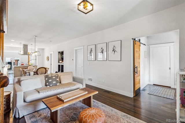 living room with a barn door and dark wood-type flooring