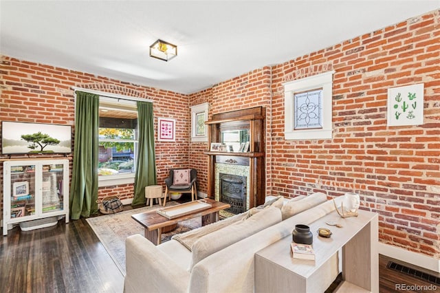 living room featuring dark hardwood / wood-style floors, a fireplace, and brick wall