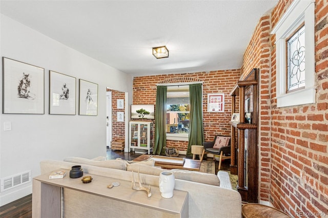 living room featuring brick wall and dark hardwood / wood-style floors