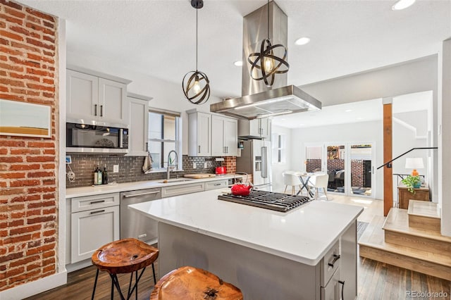 kitchen featuring sink, a kitchen breakfast bar, tasteful backsplash, island exhaust hood, and appliances with stainless steel finishes