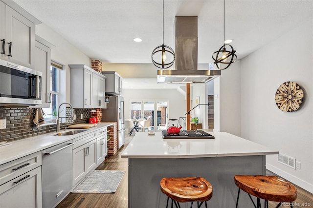 kitchen featuring sink, range hood, pendant lighting, decorative backsplash, and appliances with stainless steel finishes