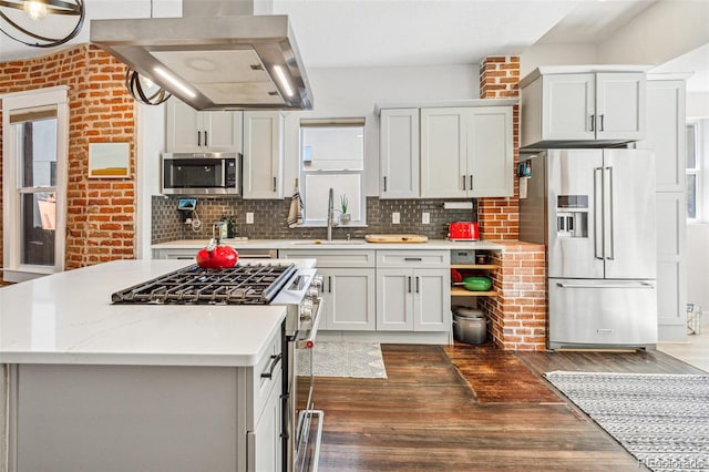 kitchen featuring white cabinetry, range hood, high quality appliances, and brick wall