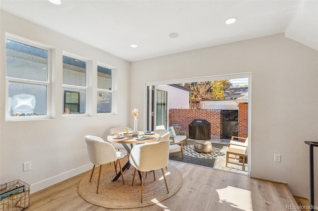 dining area featuring lofted ceiling, light hardwood / wood-style floors, and a wood stove