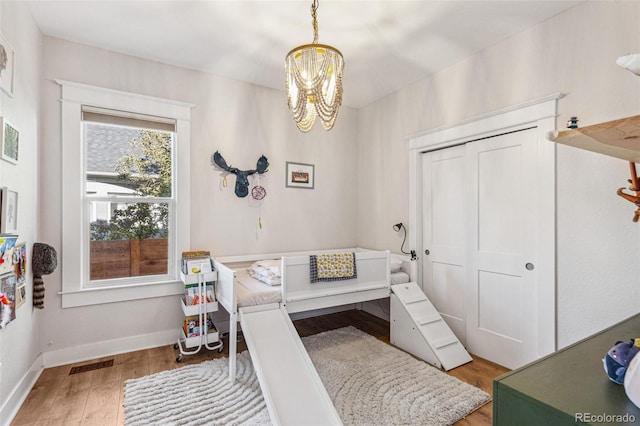 bedroom featuring a chandelier, wood-type flooring, and a closet