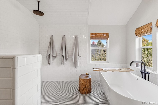 bathroom with vaulted ceiling, sink, tile walls, and a washtub