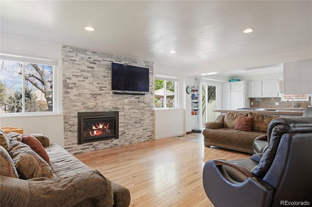 living area with baseboards, recessed lighting, light wood finished floors, and a fireplace