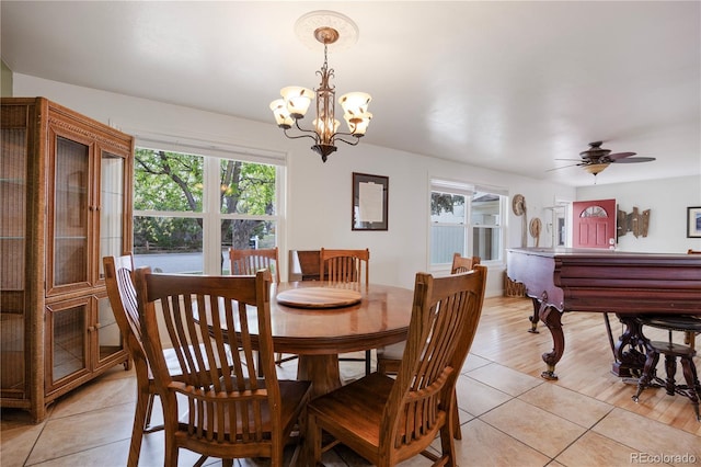 dining space featuring ceiling fan with notable chandelier, light tile patterned flooring, and a wealth of natural light