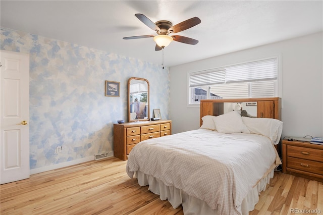 bedroom featuring visible vents, light wood-style floors, baseboards, wallpapered walls, and a ceiling fan