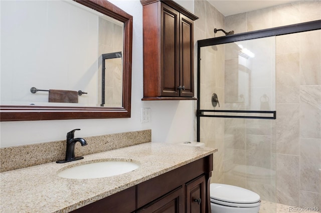 bathroom with vanity, a stall shower, and toilet