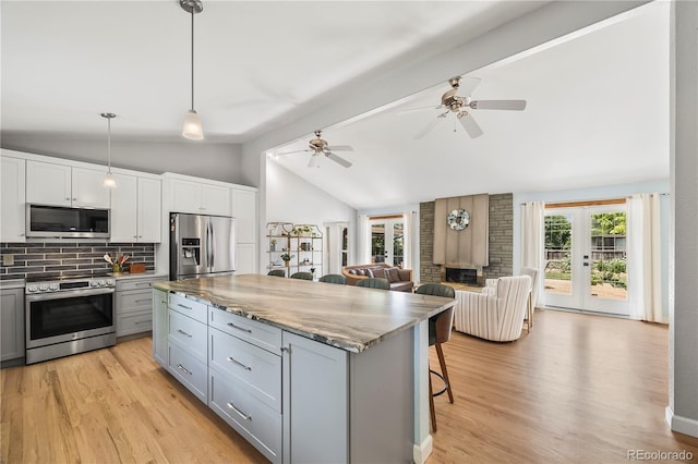 7767 S Depew St, Littleton, CO 80128 - kitchen featuring appliances with stainless steel finishes, gray cabinets, tasteful backsplash, a center island, and open floor plan