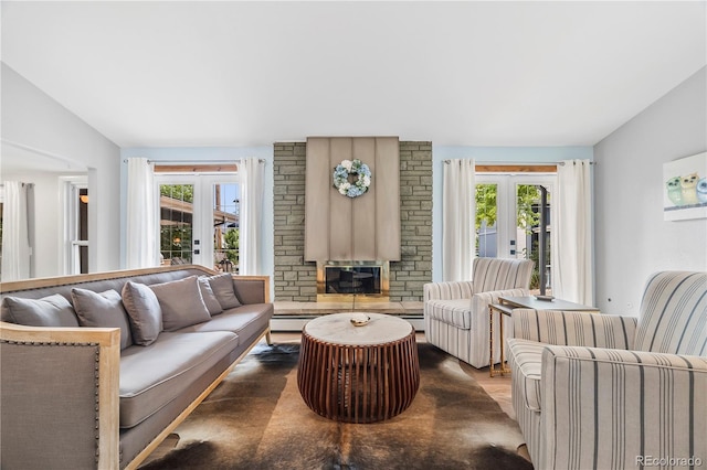 7767 S Depew St, Littleton, CO 80128 - living area featuring vaulted ceiling, french doors, a stone fireplace, and wood finished floors