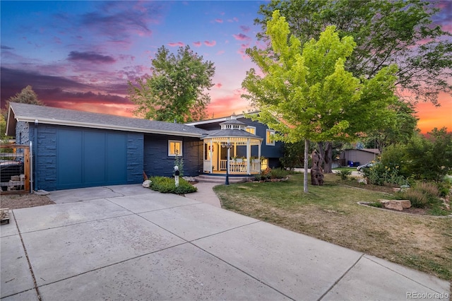7767 S Depew St, Littleton, CO 80128 - view of front of home with concrete driveway, an attached garage, a front yard, a porch, and stone siding