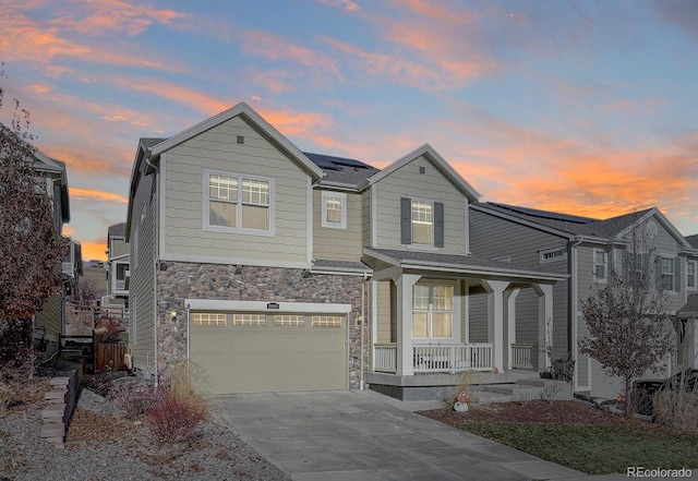 view of front of home with a porch, a garage, and solar panels