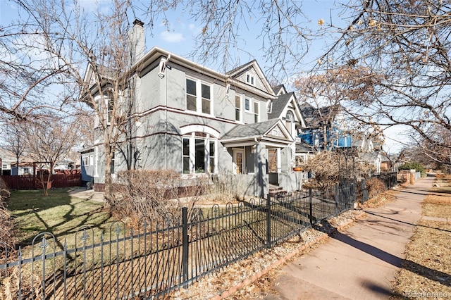 view of front facade with a fenced front yard, a front yard, and a chimney