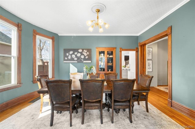 dining room with an inviting chandelier, crown molding, wood finished floors, and baseboards