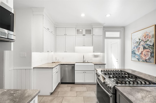 kitchen featuring backsplash, white cabinets, appliances with stainless steel finishes, and a sink